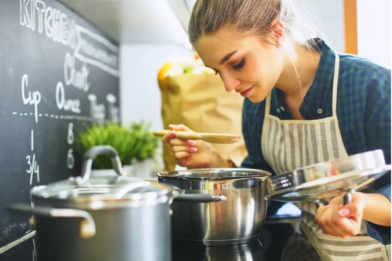 young woman cooking in the kitchen smelling the food from the caserole